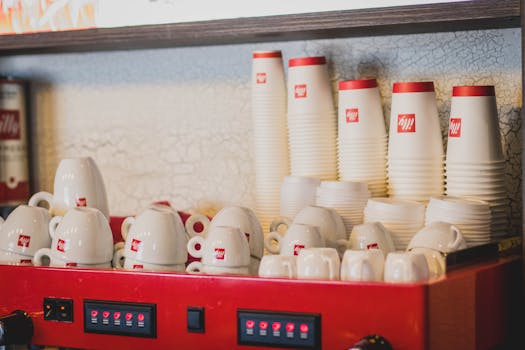A vibrant display of stacked coffee cups and a coffee machine inside a café.
