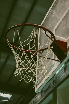 Detailed shot of a basketball hoop inside a sports hall, ideal for sports themes.