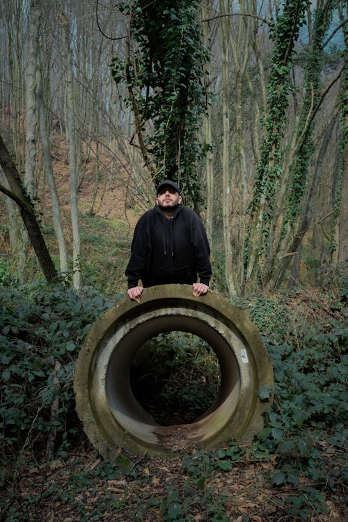 A Man Standing next to a Concrete Crawl Tunnel in the Forest 