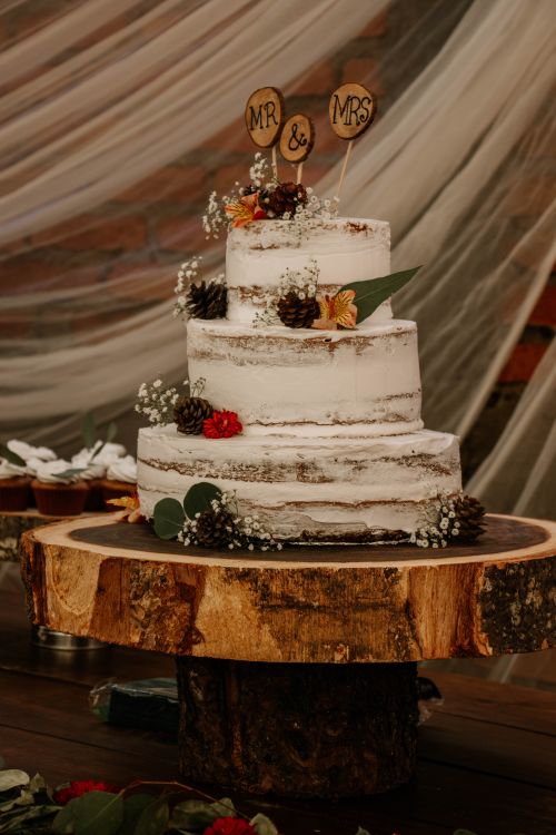 Free Rustic three-tiered wedding cake with natural decorations on a wooden stand. Stock Photo