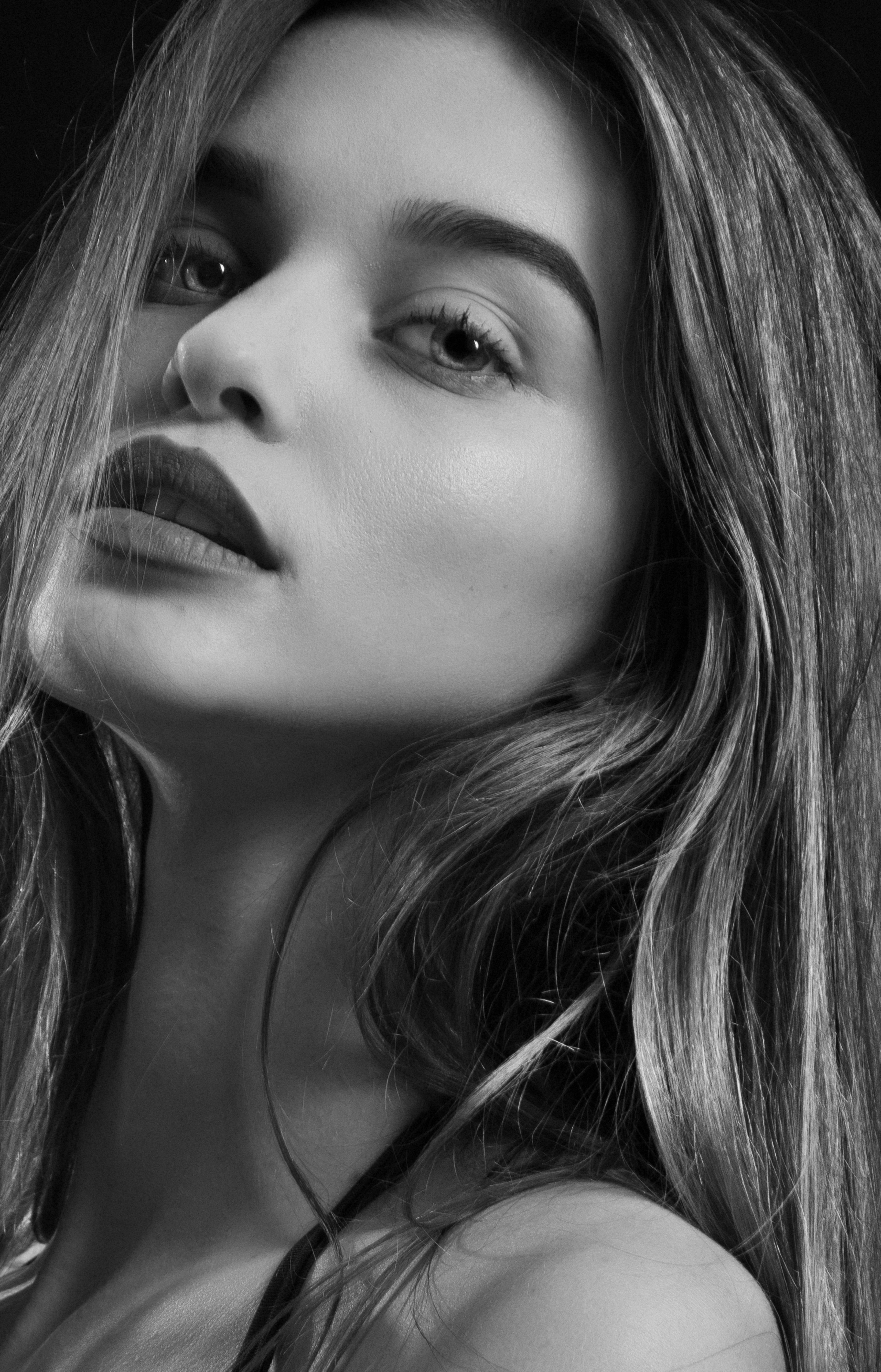 Stylish black and white portrait of a young woman with flowing hair and striking features.