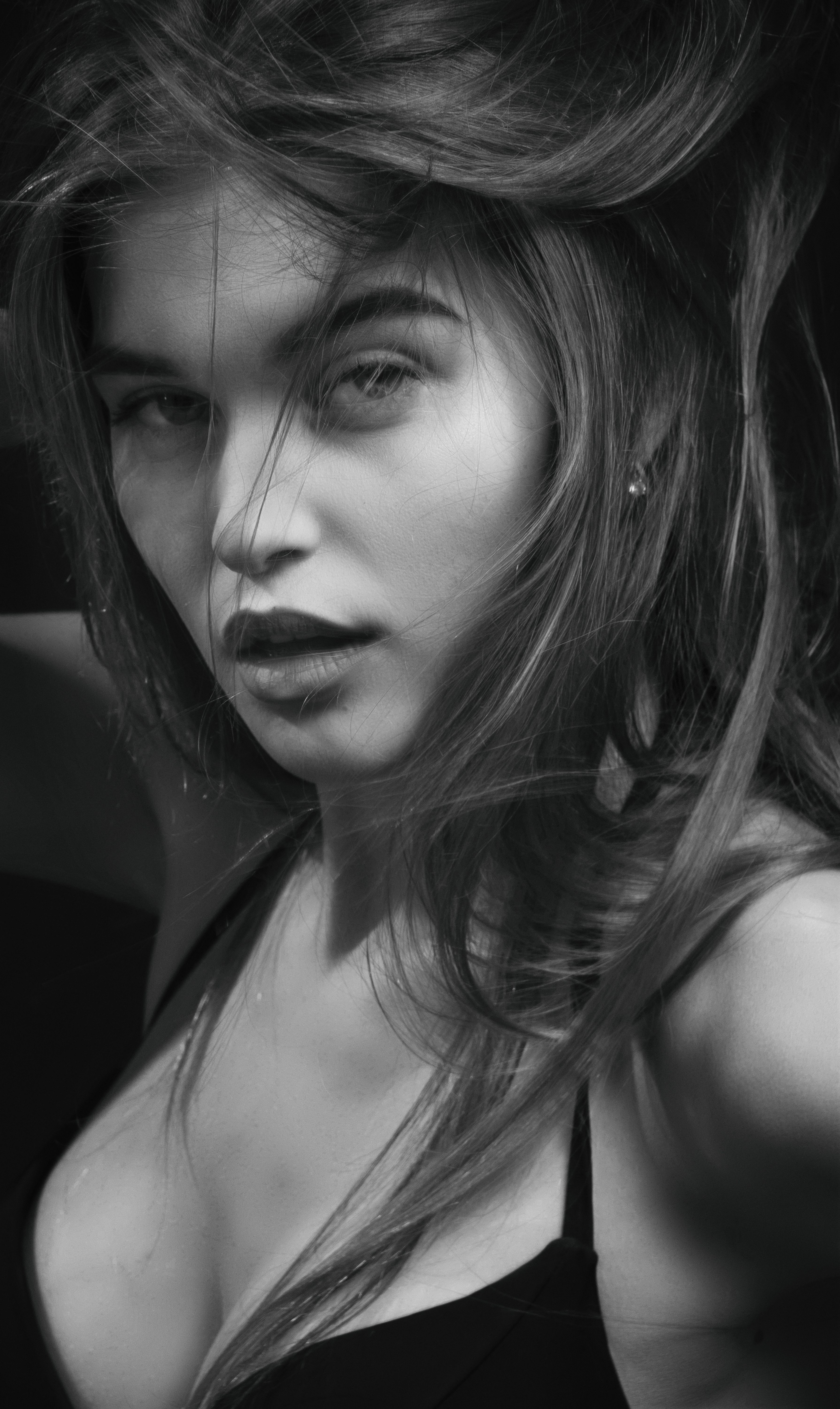 Captivating black and white portrait of a sensual woman with tousled hair and intense gaze.