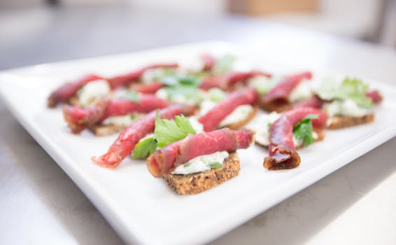 Beef carpaccio with creamy spread on toasted bread garnished with herbs.