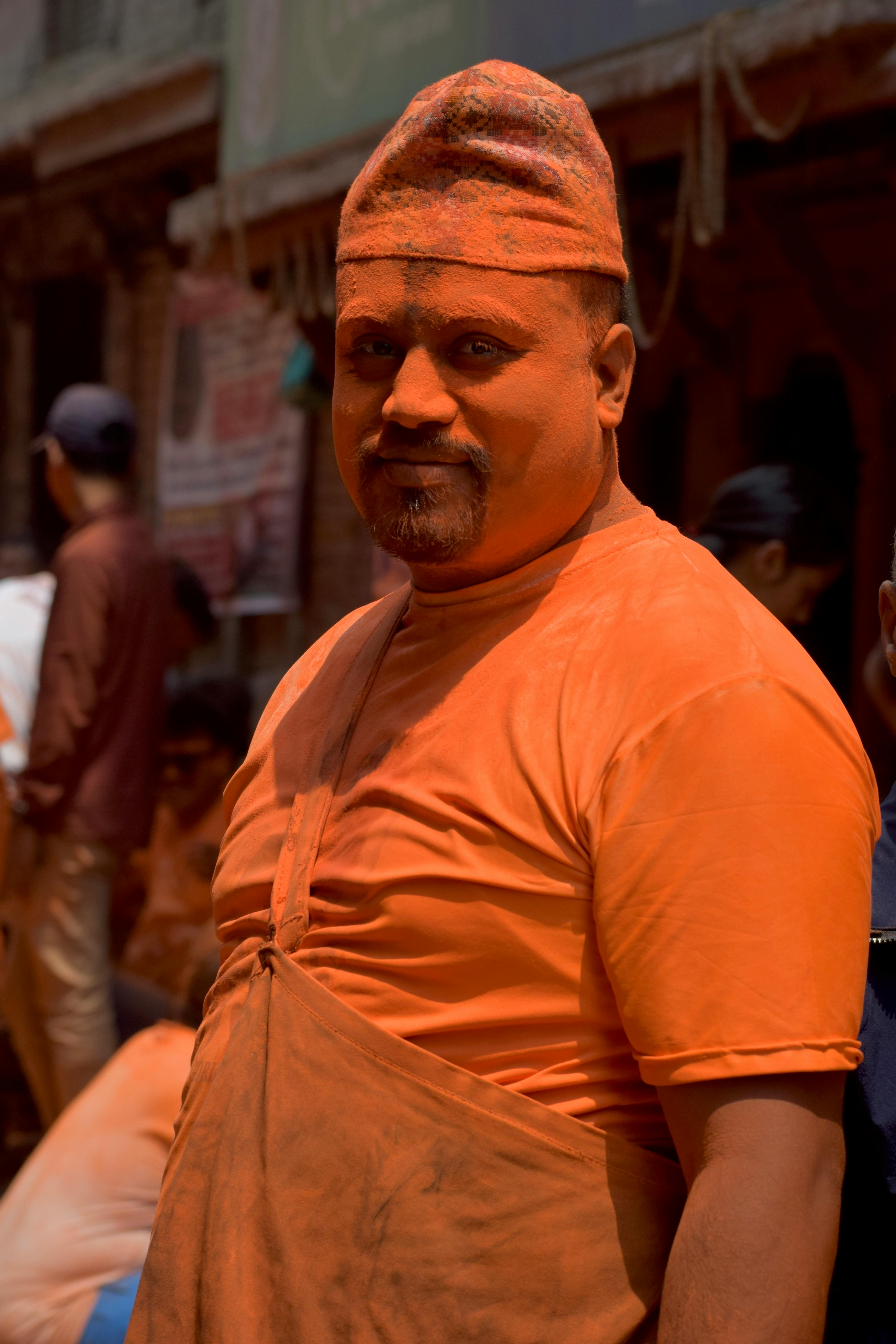 A man dressed in orange and covered in orange powder at the vibrant Bisket Jatra festival in Nepal.