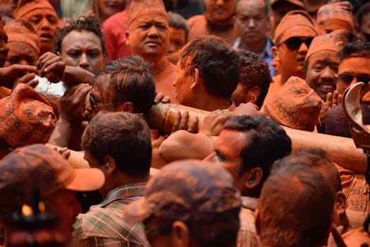 Men carrying a wooden beam during the traditional Bisket Jatra festival in a crowded, vibrant setting in Nepal.