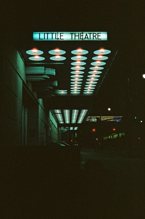 Free Moody night scene of Little Theatre in Kansas City, showcasing its illuminated sign and urban surroundings. Stock Photo