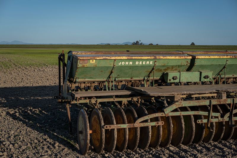 A John Deere seeder stands ready in a vast open field