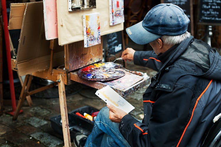 Man Holding Brush While Painting In Front Of Easel