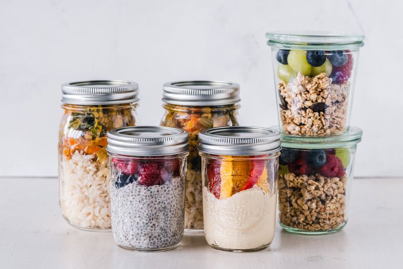 Close-up of healthy food jars containing granola, fruits, and yogurt.