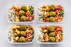 Colorful meal prep containers with falafel, chickpeas, rice, and vegetables for a healthy lifestyle.