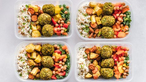 Colorful meal prep containers with falafel, chickpeas, rice, and vegetables for a healthy lifestyle.