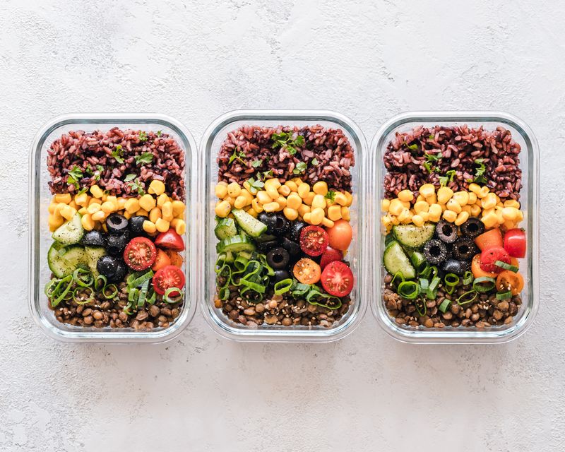 cooked rice divided into three containers with different toppings