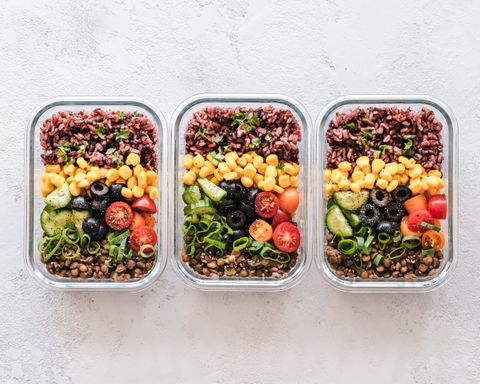 Three glass containers with red rice, corn, olives, tomatoes, cucumber and lentils