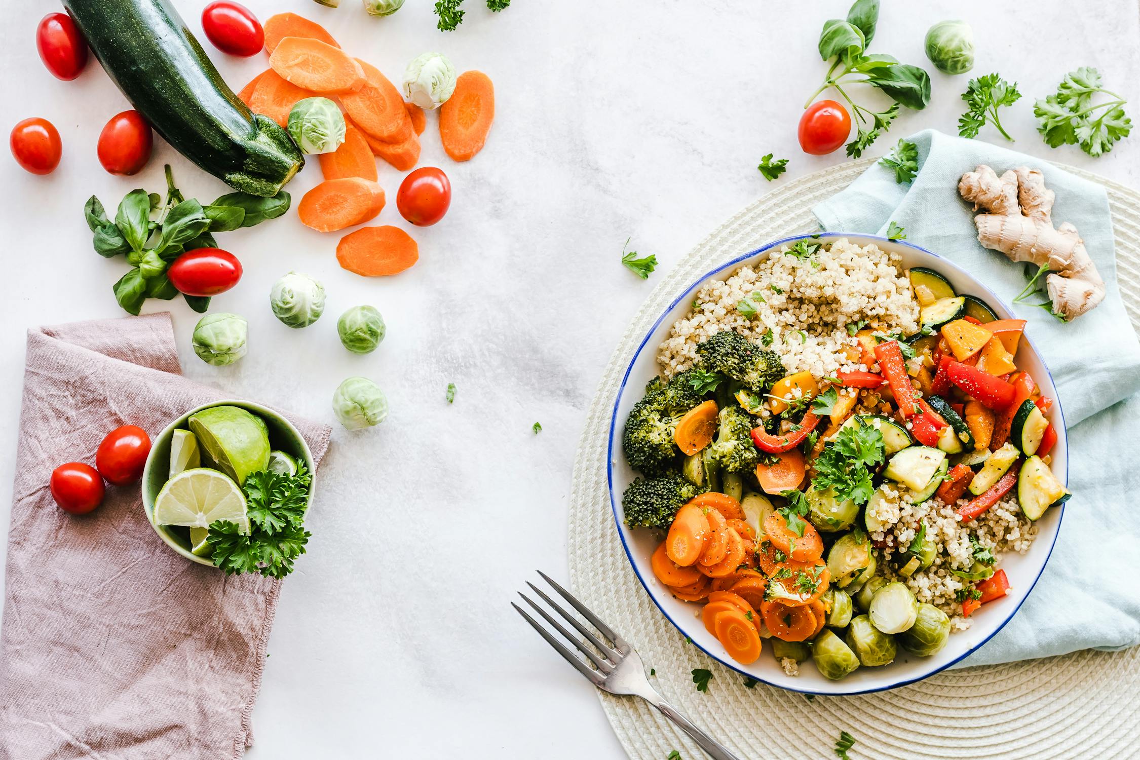 A birds eye view of a table with a white table cloth and various veggies and grain dishes. Photo by pexels user Ella Olsson. Photo used courtesy of Pexels.com.