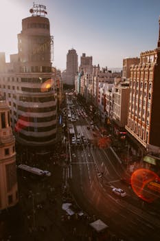 Bustling cityscape of Madrid's Gran Vía at sunset with iconic buildings and busy streets.