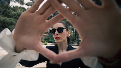 Woman in Sunglasses behind Hands