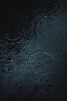 Close-up of raindrop ripples forming natural patterns on water.