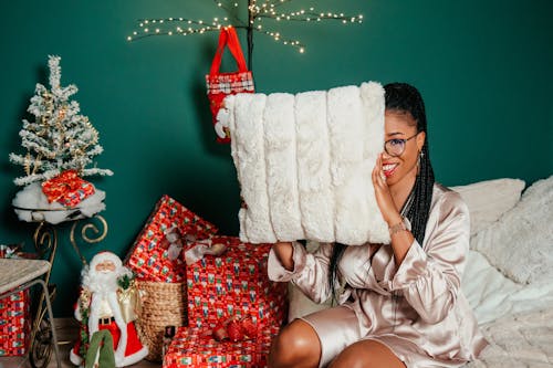 Woman Holding Pillow near Christmas Decorations and Posing