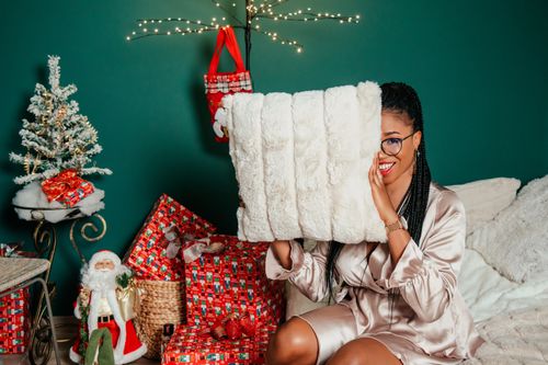 Free Woman enjoying Christmas morning with gifts, tree, and cozy decor. Stock Photo