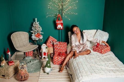 Woman Sitting on Bed and Posing with Christmas Decorations and Gifts around