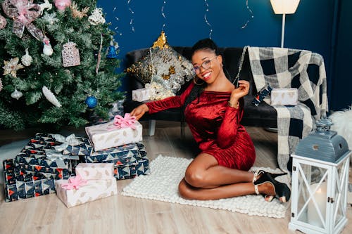 Woman Sitting near Christmas Tree and Gifts and Posing