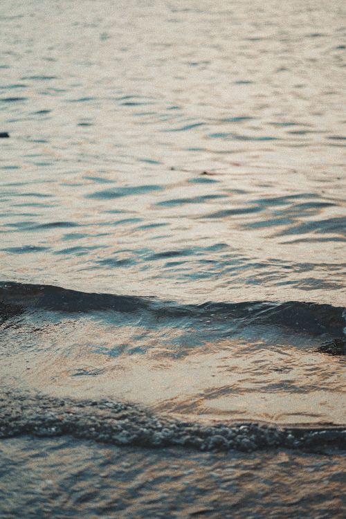 Free Tranquil image capturing gentle ocean waves during a peaceful sunset. Stock Photo