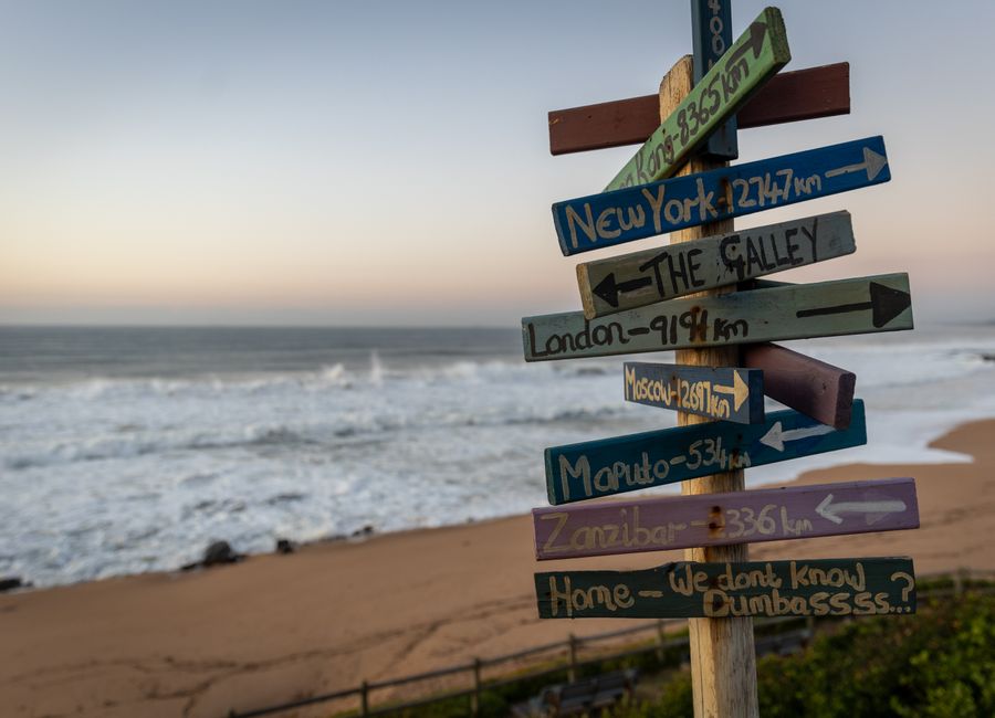 A vibrant signpost with city names at a beach on Dolphin Coast, South Africa.