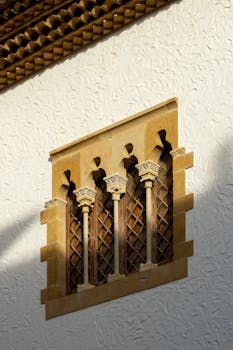 A close-up view of a decorative window featuring ornate columns on a textured wall in Sitges, Spain.
