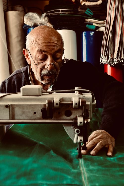 Free An elderly man skillfully operates a sewing machine, showcasing craftsmanship. Stock Photo