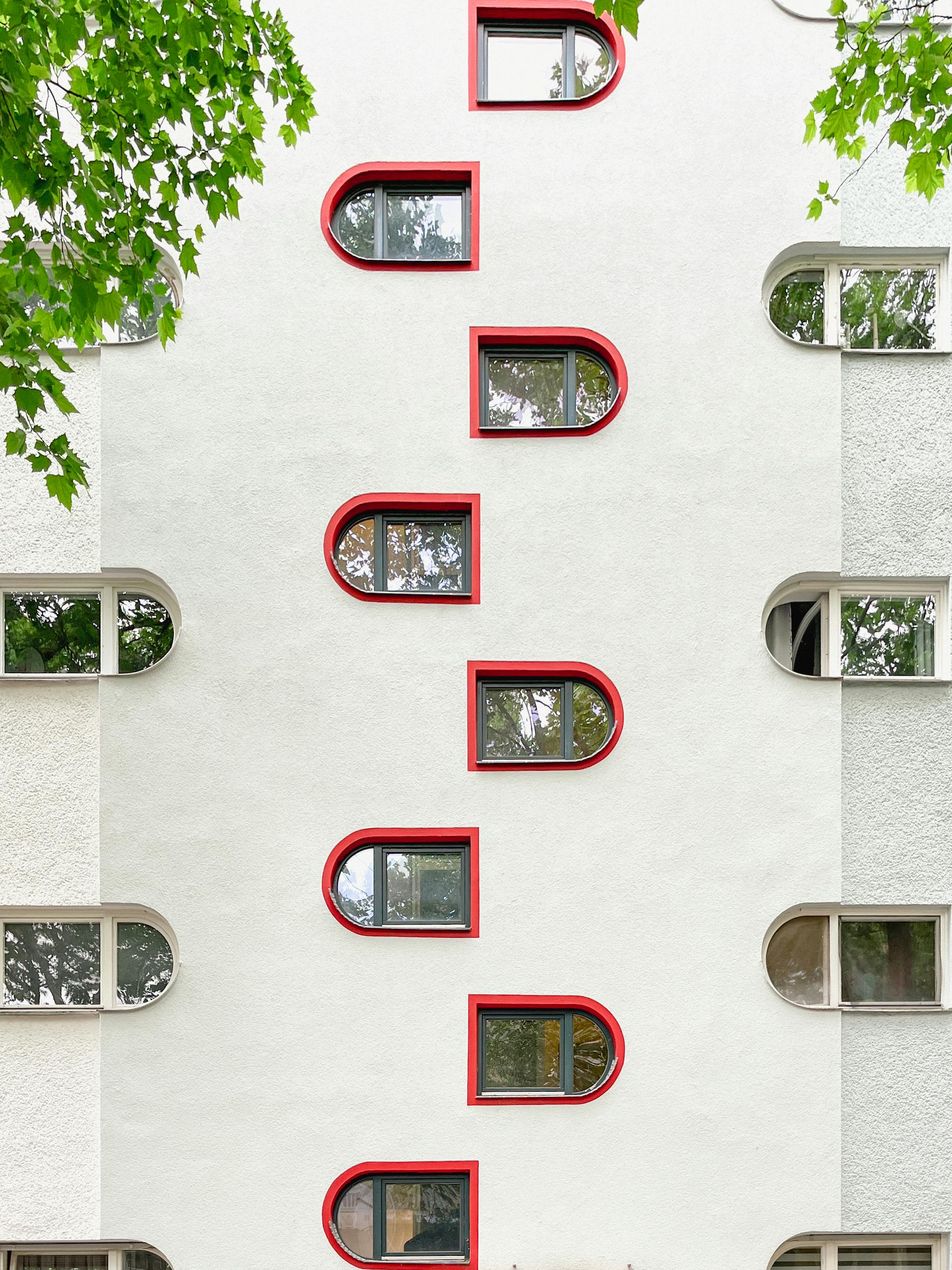 Vertical view of a modern residential building with distinct red-framed windows in Berlin, Germany.