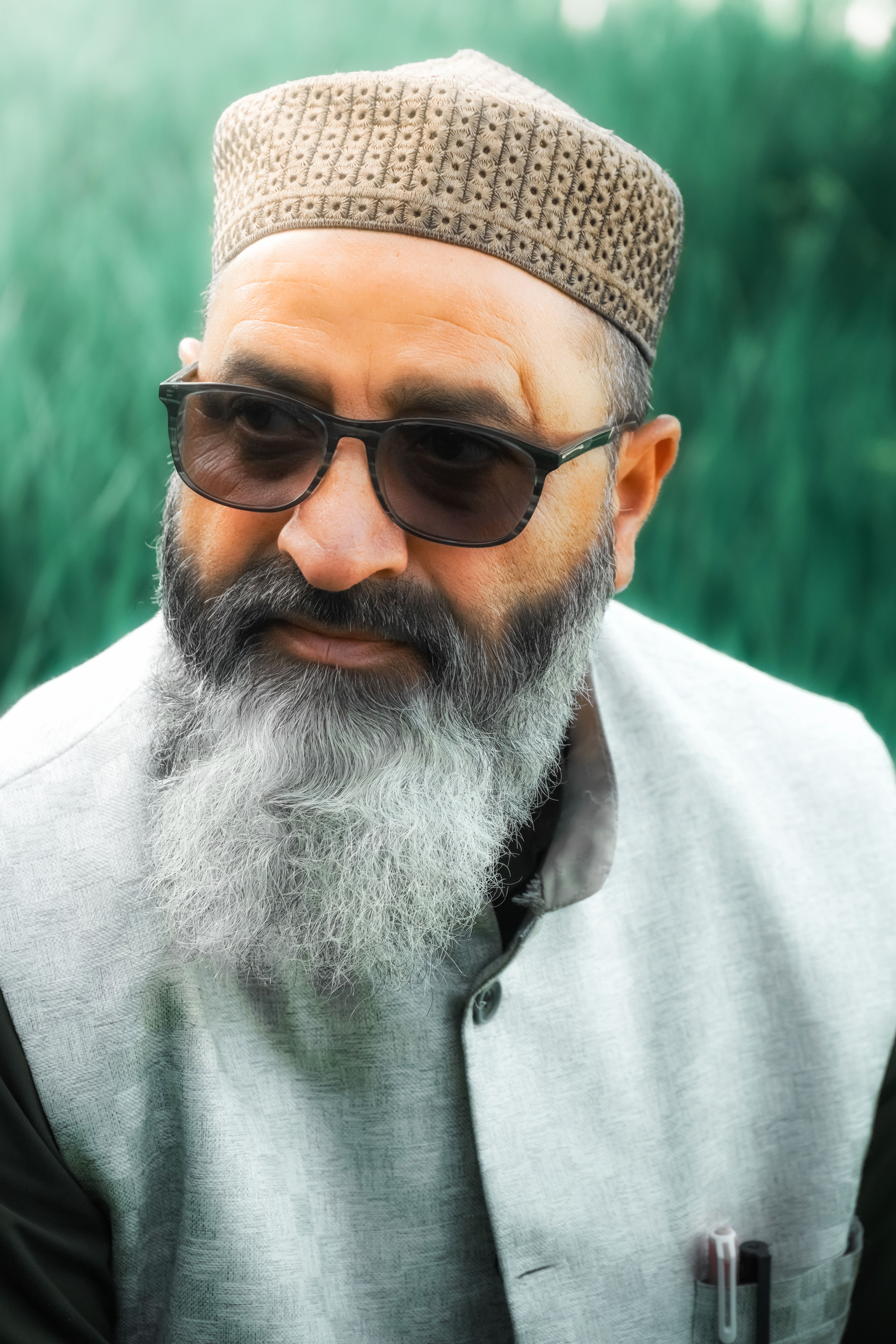 Elegant portrait of a mature man with gray beard wearing traditional clothing outdoors.