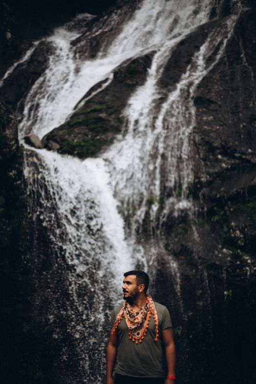 Free Young man poses near a cascading waterfall in Türkiye, showcasing adventure and travel. Stock Photo