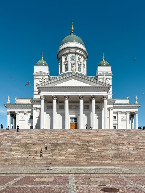 A sunlit view of the iconic Helsinki Cathedral with a clear blue sky in the background.