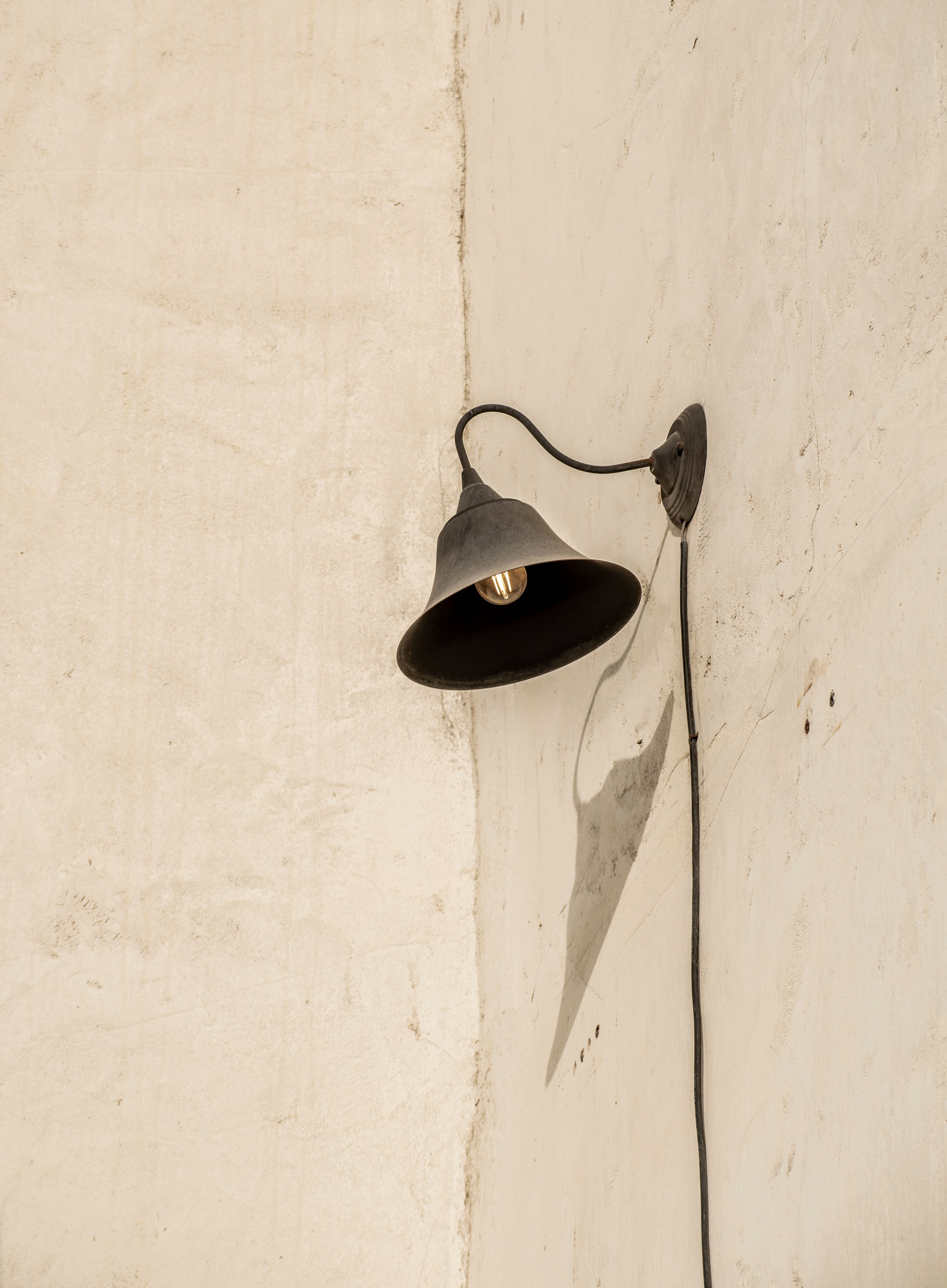 Wall lamp casting a hard shadow on a textured wall — aboodi vesakaran on Pexels
