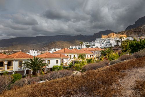 Free Picturesque view of Costa Adeje, CN, Spain, featuring villas against a mountain backdrop under a dramatic sky. Stock Photo