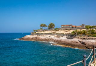 Beautiful coastal scenery at Costa Adeje, with clear blue waters and rocky cliffs under a sunny sky.