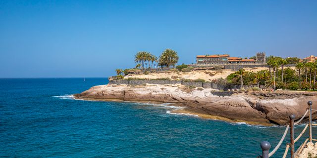 Beautiful coastal scenery at Costa Adeje, with clear blue waters and rocky cliffs under a sunny sky.