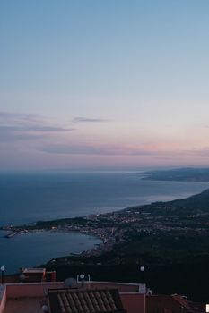 Breathtaking aerial view of Castelmola and Sicilian coast during a serene sunset.