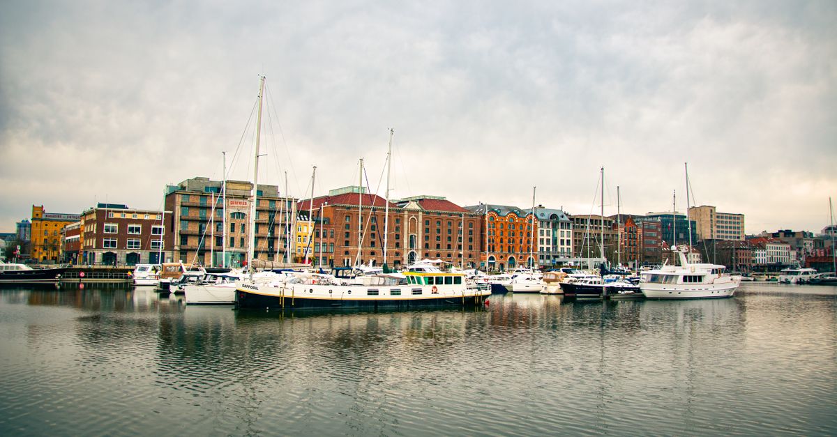 Scenic view of a harbor with boats moored in front of a colorful urban skyline.