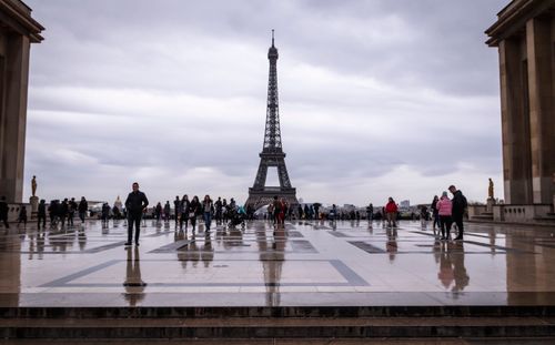 Free Tourists exploring Trocadéro Square with a stunning Eiffel Tower view on a cloudy day in Paris. Stock Photo