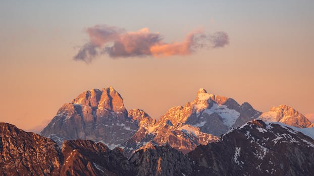 Stunning view of the Italian Alps under a warm sunset glow, with snow-capped peaks.