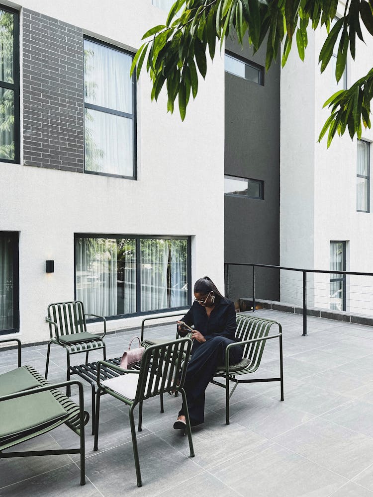 Woman Sitting On A Terrace Of A Modern Residential Building 