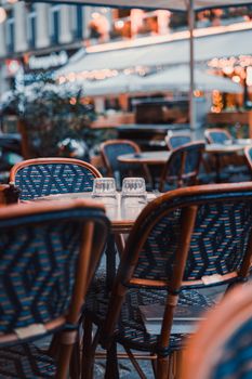 Charming Paris outdoor café scene with wicker chairs and tables, perfect for urban lifestyle and travel themes.