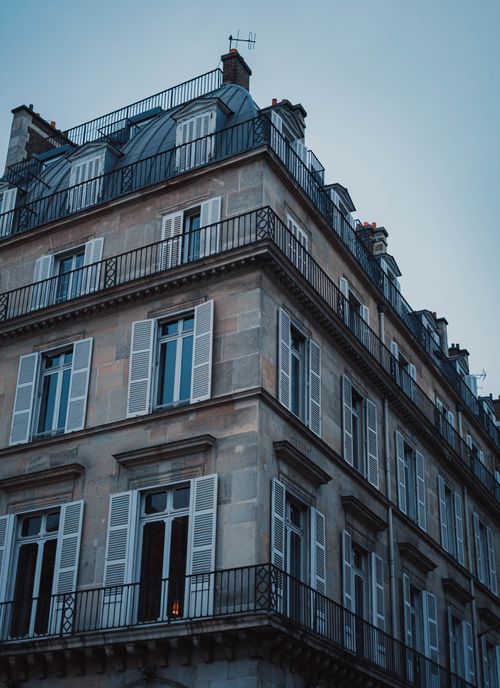 Free Low angle shot of a classic Parisian building corner with balconies and shuttered windows. Stock Photo