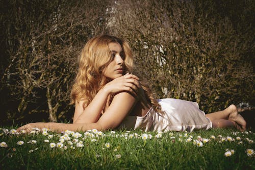 Woman in White Dress Lying Down among Flowers