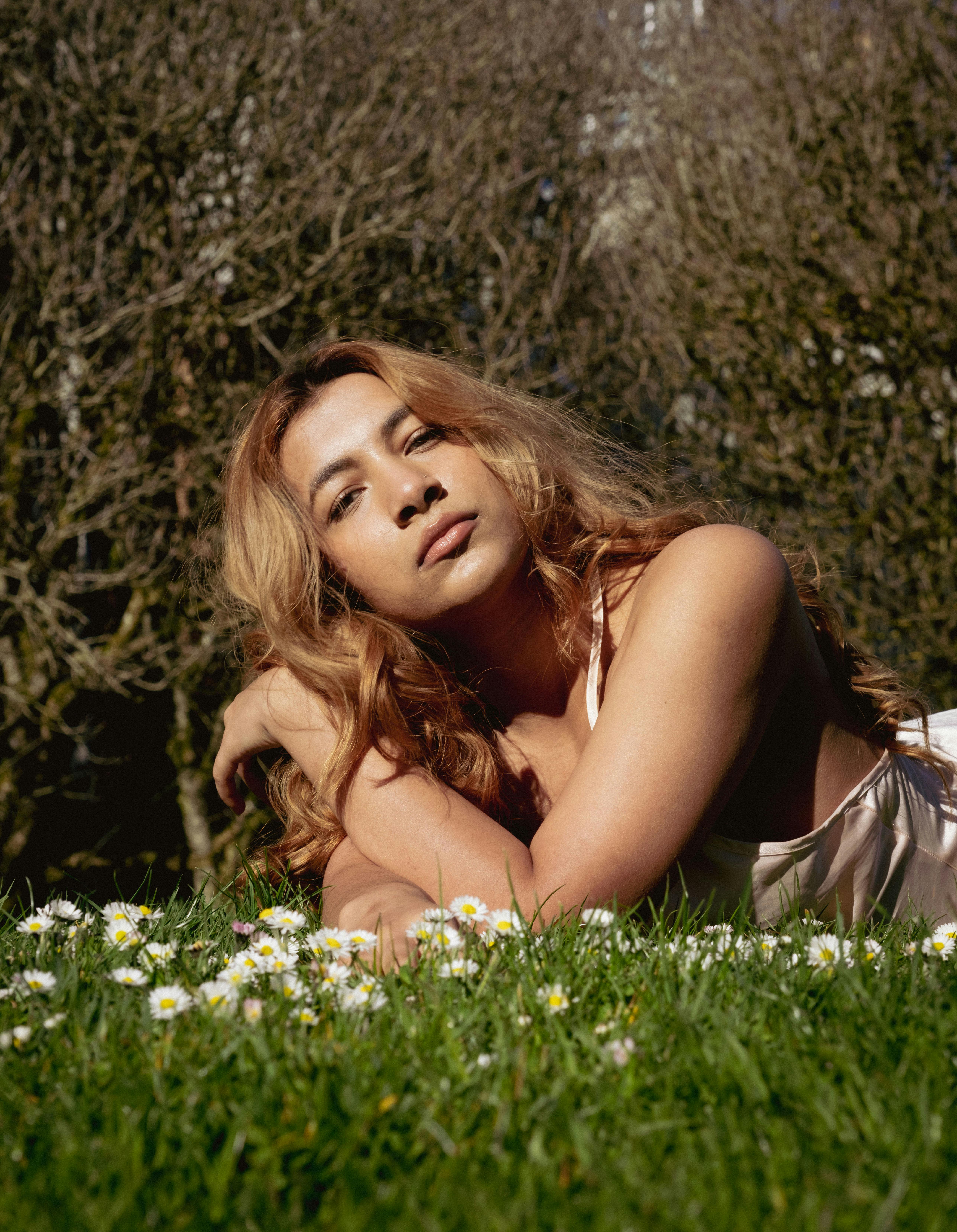 Woman with long brown hair lying in a sunlit meadow, captured in Vancouver.