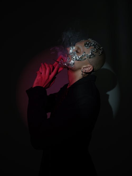 Studio Shot of a Man Wearing Jewelry on the Face and Smoking 