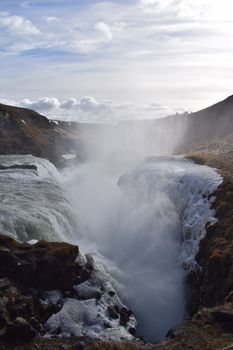 Stunning view of the powerful Gullfoss waterfall surrounded by beautiful Icelandic landscape.
