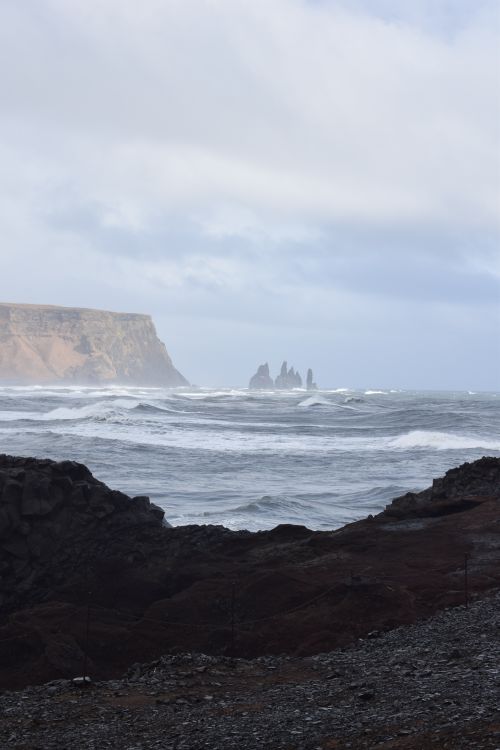 Free Breathtaking view of Iceland's rocky coast and Reynisdrangar sea stacks under a cloudy sky. Stock Photo