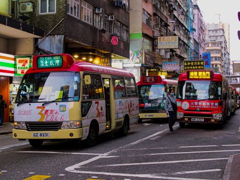 Bustling Hong Kong street with colorful mini buses and vibrant city life.